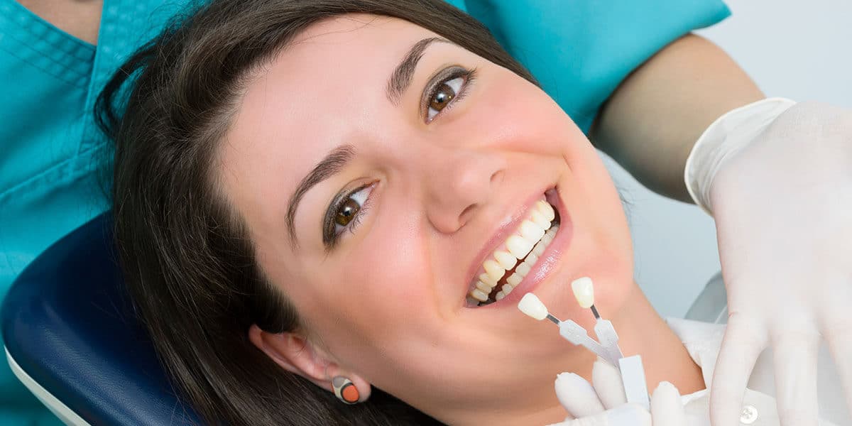 Woman in dental chair with tooth shade guide